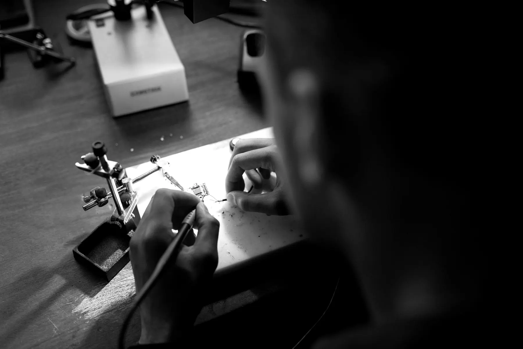 A workbench with a soldering station and a board clamped in a holder