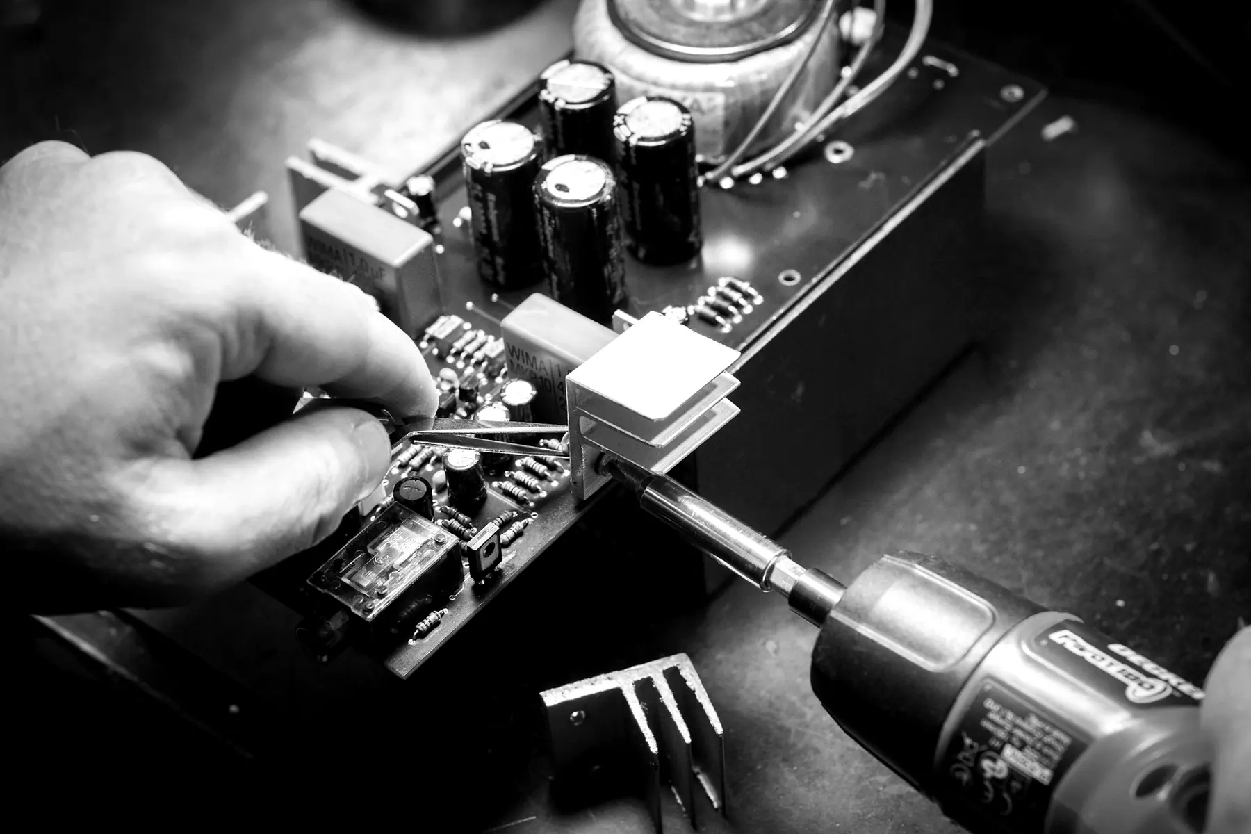 Hands repairing an amplifier board with a soldering iron